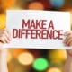 person holds a sign that says "make a difference"