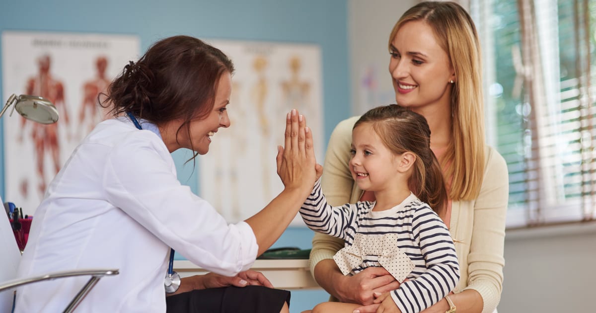 Image of a pediatrician high-fiving a young patient in the exam room